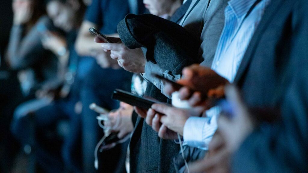 Menschen in einer Reihe schauen auf ihre Smartphones.